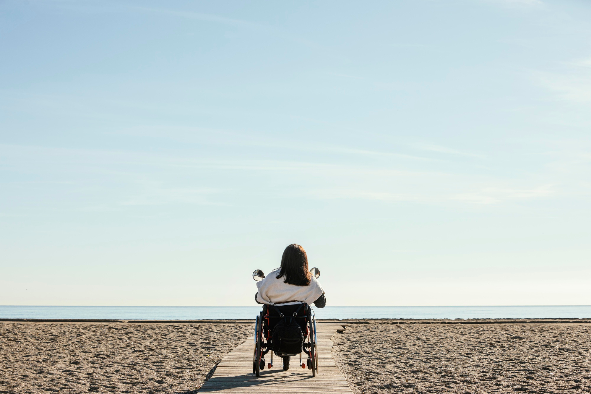 NDIS Holiday Accommodation - Back View of Woman in Wheelchair at Beach