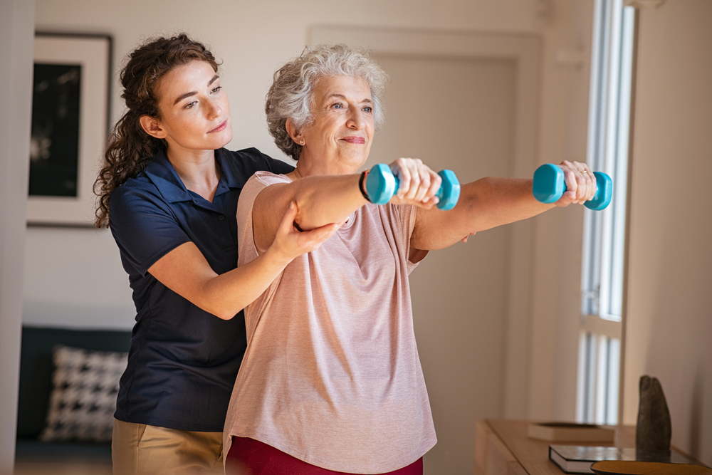 A professional and well-trained female expert provides exercise to an elderly woman in aged care.