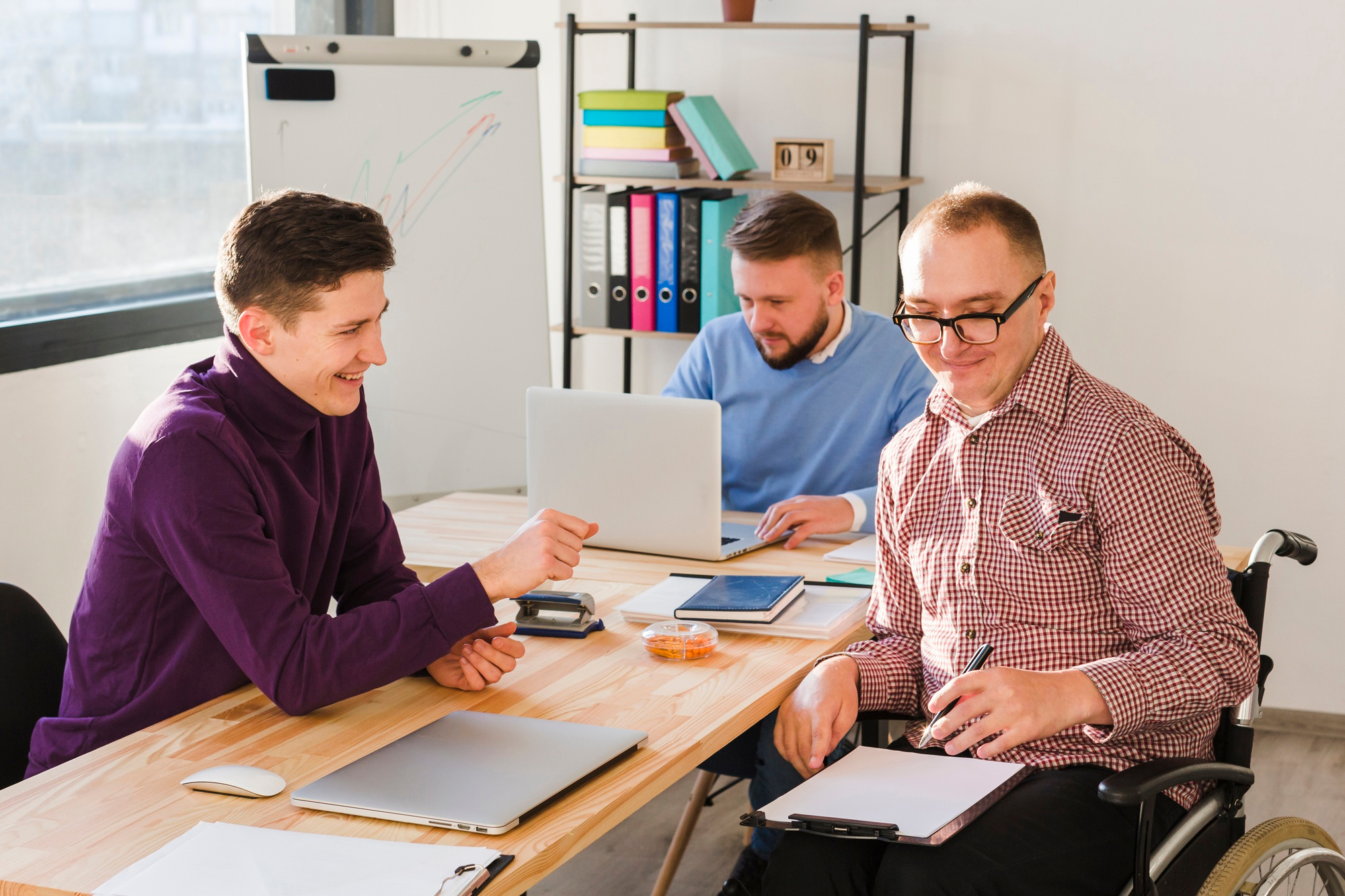 An NDIS Support Coordinator from SafeLane Healthcare discussing about NDIS Plan with his participant, they're sitting around the table and have essential documents on the table